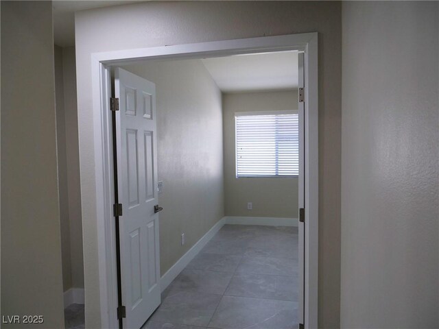 corridor with light tile patterned floors and baseboards