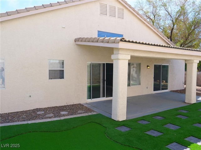 rear view of property with a tile roof, a patio, and stucco siding