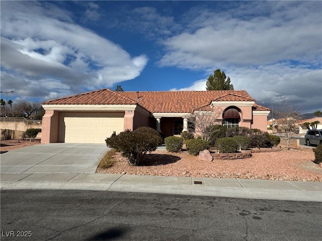 mediterranean / spanish-style home with a garage, a tiled roof, concrete driveway, and stucco siding