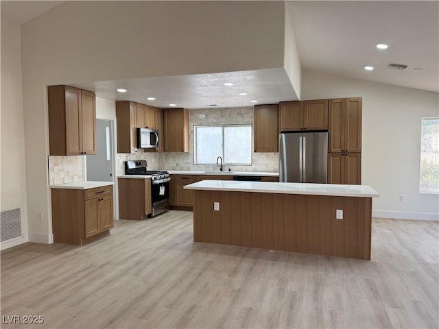 kitchen featuring vaulted ceiling, appliances with stainless steel finishes, visible vents, and a center island