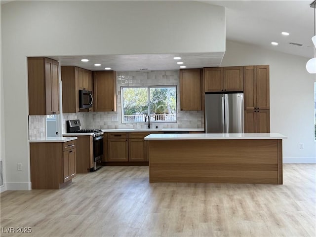 kitchen featuring brown cabinets, a sink, stainless steel appliances, light countertops, and vaulted ceiling