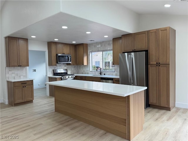 kitchen with lofted ceiling, light wood-type flooring, appliances with stainless steel finishes, and a sink