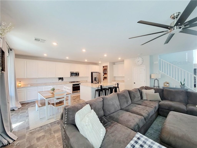 living area featuring stairs, ceiling fan, visible vents, and recessed lighting