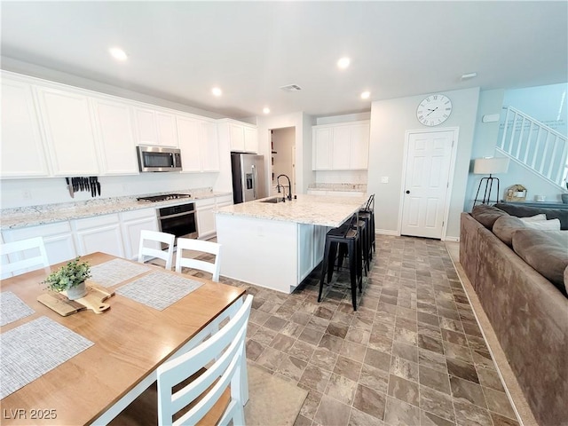 kitchen with an island with sink, stainless steel appliances, a sink, and recessed lighting