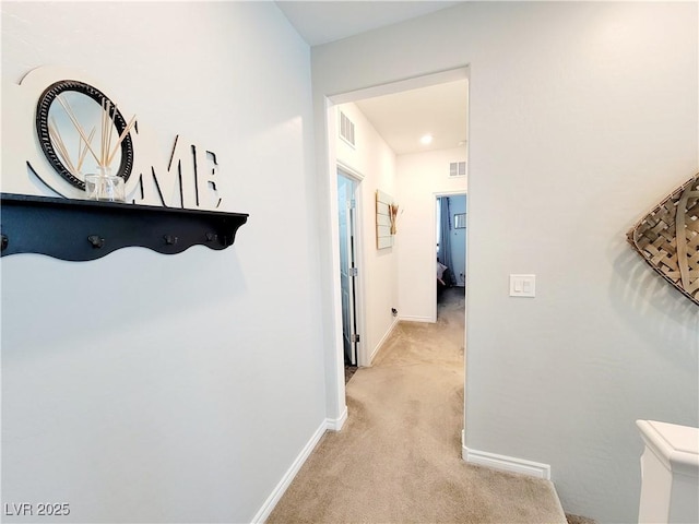 corridor with light carpet, baseboards, and visible vents