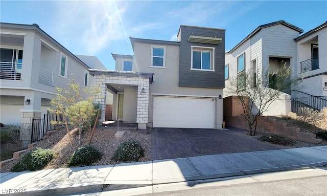 contemporary house featuring a garage, decorative driveway, fence, and stucco siding