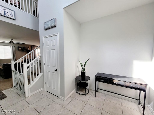 staircase with ceiling fan, baseboards, and tile patterned floors