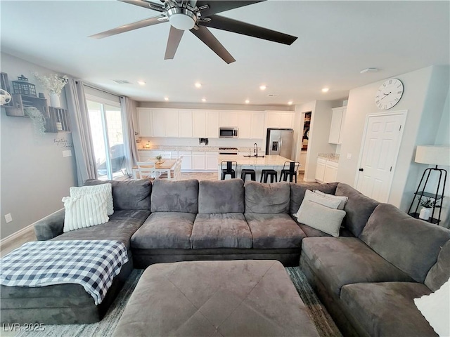 living area featuring baseboards, visible vents, a ceiling fan, and recessed lighting