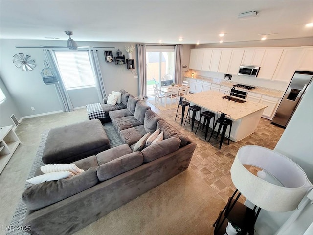 living area with a ceiling fan, recessed lighting, and baseboards