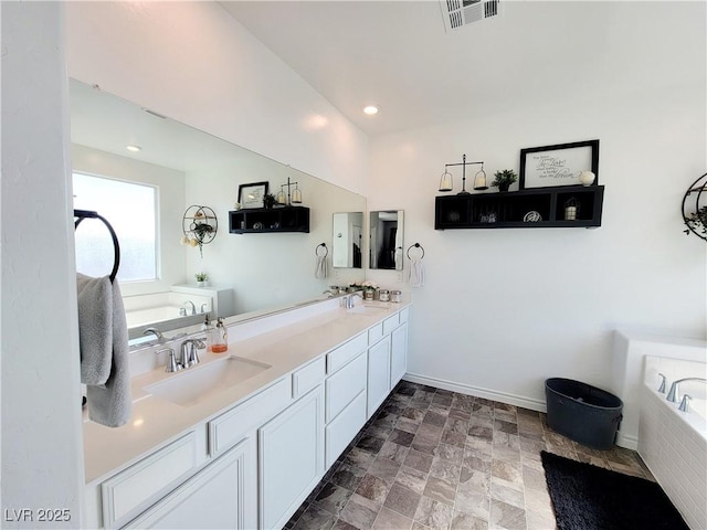 bathroom with a garden tub, visible vents, and a sink