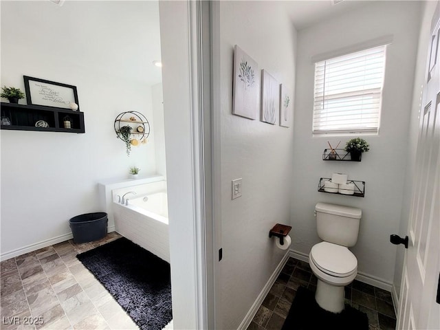 bathroom with baseboards, toilet, and a bath