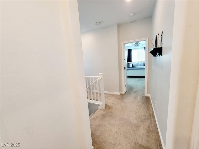 corridor with carpet flooring, an upstairs landing, and baseboards