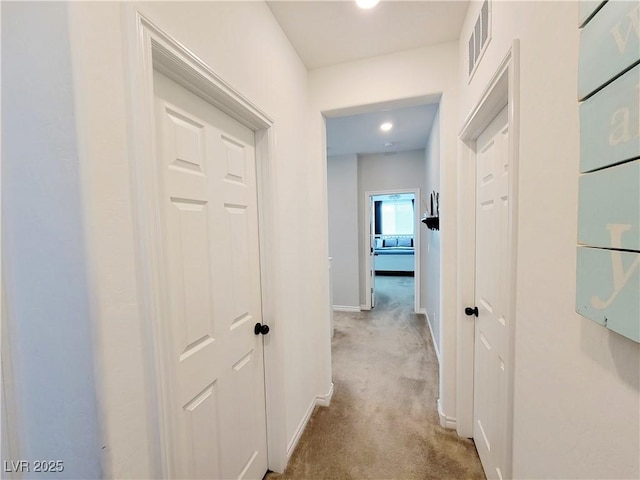 hall featuring carpet floors, baseboards, and visible vents