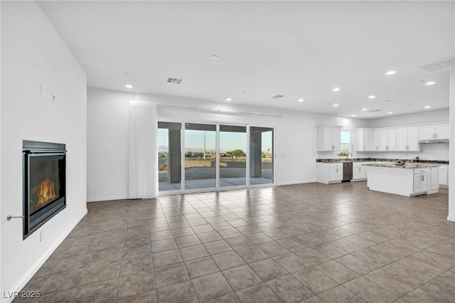 unfurnished living room with recessed lighting, visible vents, and a glass covered fireplace