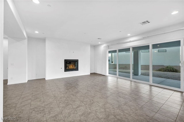 unfurnished living room featuring baseboards, a glass covered fireplace, visible vents, and recessed lighting