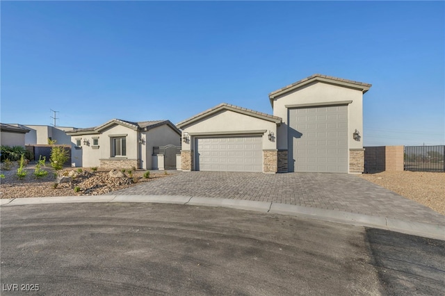 view of front facade with a garage, stone siding, fence, decorative driveway, and stucco siding