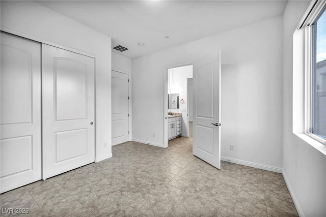 unfurnished bedroom with baseboards, visible vents, a closet, and ensuite bathroom