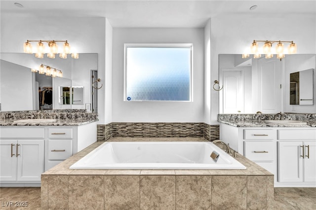 bathroom featuring two vanities, a sink, and a bath