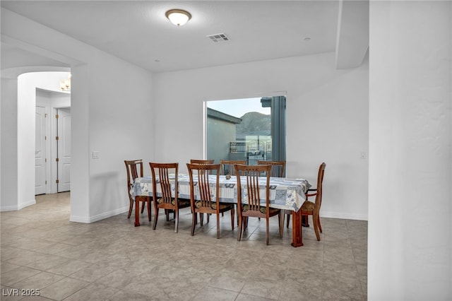 dining space with arched walkways, visible vents, and baseboards