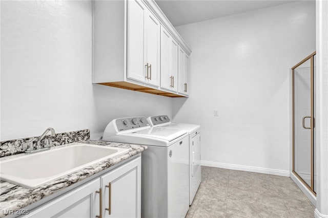 clothes washing area with washing machine and dryer, a sink, cabinet space, and baseboards