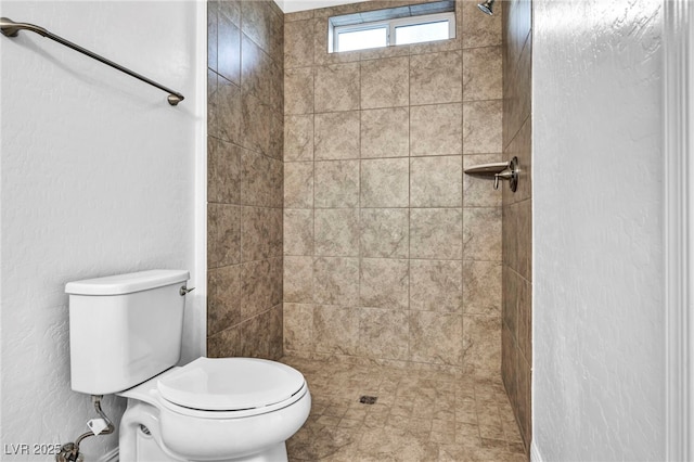 bathroom featuring a tile shower and toilet