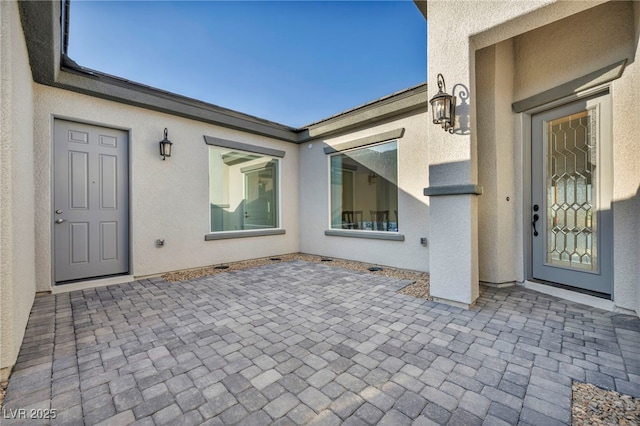 entrance to property featuring a patio and stucco siding