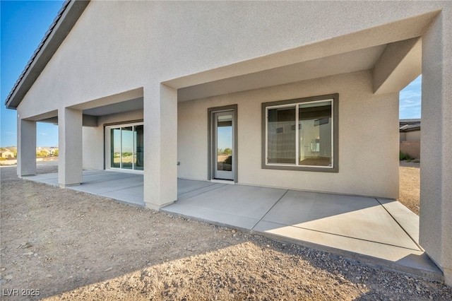 back of property with a patio and stucco siding