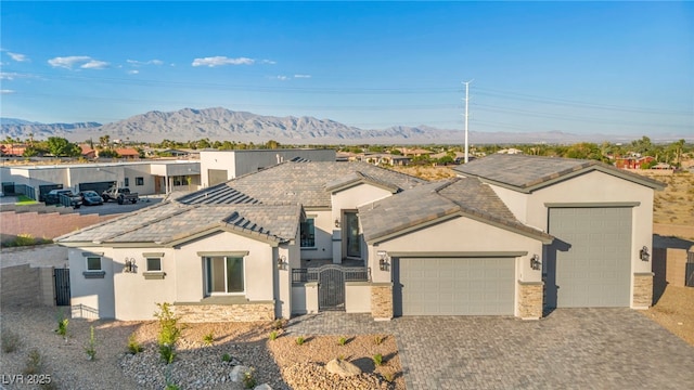 ranch-style home featuring a fenced front yard, decorative driveway, stucco siding, a gate, and a garage