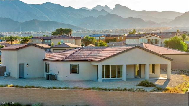 rear view of property featuring a mountain view, central air condition unit, a tile roof, a residential view, and stucco siding