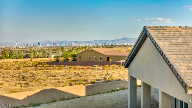 exterior space featuring a tile roof, fence, a mountain view, and stucco siding