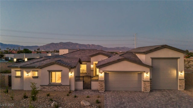 view of front of house with a garage, fence, decorative driveway, a gate, and stucco siding