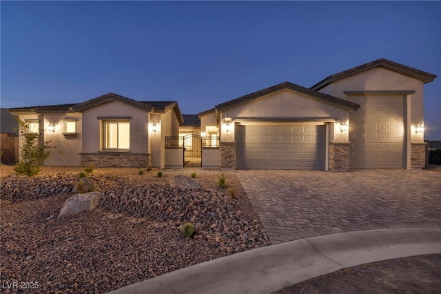 view of front of house with a garage, stone siding, decorative driveway, and a gate