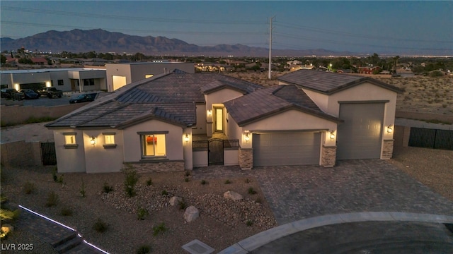 view of front of house with a garage, decorative driveway, a mountain view, and stucco siding