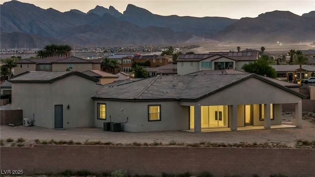 back of house at dusk featuring a residential view, a mountain view, and stucco siding