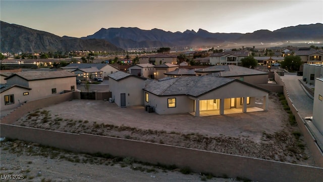 rear view of property featuring a mountain view, a fenced backyard, and a residential view