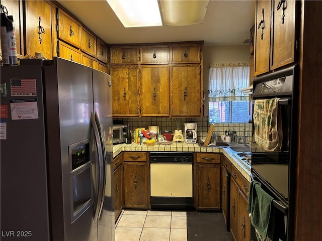 kitchen with tasteful backsplash, brown cabinets, stainless steel refrigerator with ice dispenser, and tile countertops