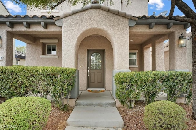 view of exterior entry with a tiled roof and stucco siding