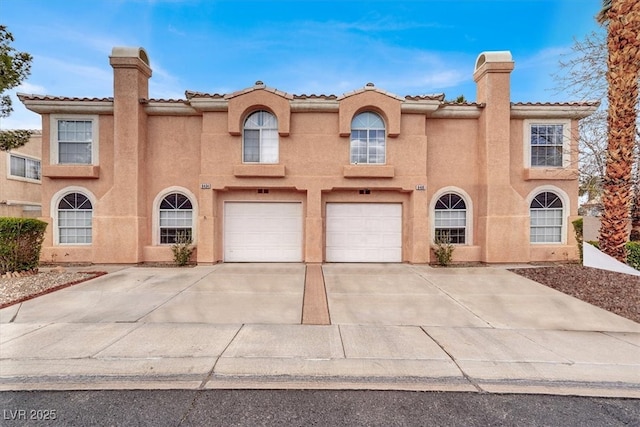 mediterranean / spanish home featuring a garage, driveway, a chimney, and stucco siding