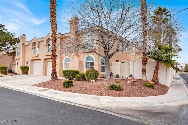 view of front of property featuring a garage, driveway, a chimney, and stucco siding