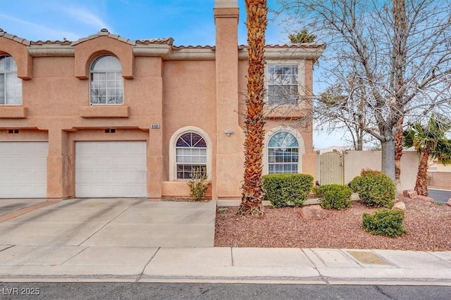 view of front of home with a garage, concrete driveway, a tile roof, a gate, and stucco siding