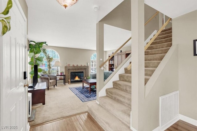 stairs featuring a tile fireplace, visible vents, baseboards, and wood finished floors