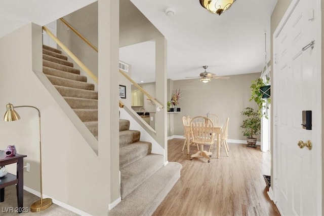 stairway featuring visible vents, ceiling fan, baseboards, and wood finished floors