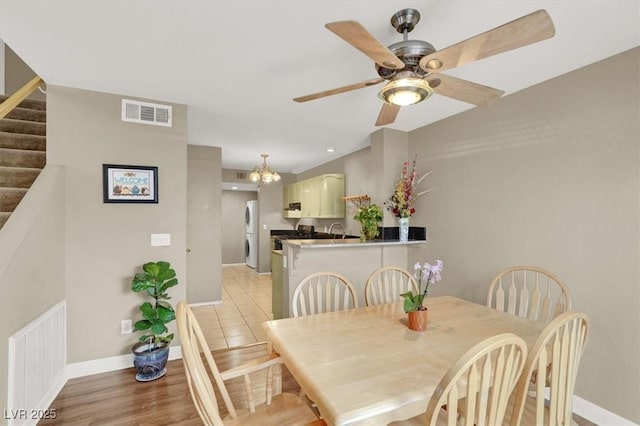 dining area featuring light wood finished floors, baseboards, stairs, and visible vents