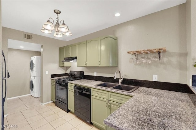 kitchen with stacked washer / dryer, a sink, green cabinetry, under cabinet range hood, and black appliances