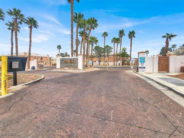 view of road with a gate, curbs, a gated entry, and street lights