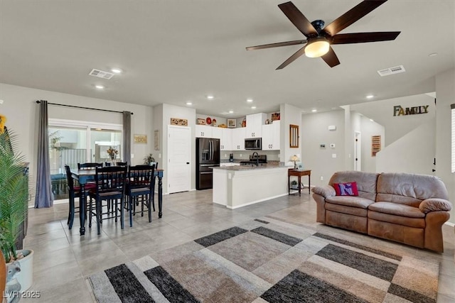 living room with ceiling fan, visible vents, and recessed lighting