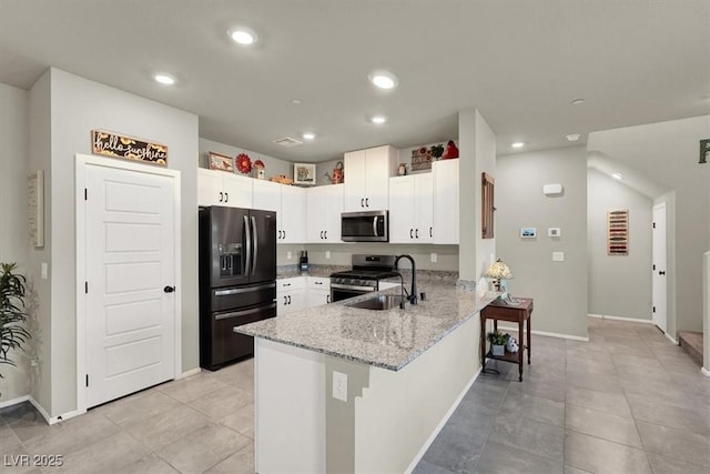 kitchen with appliances with stainless steel finishes, white cabinetry, a sink, light stone countertops, and a peninsula