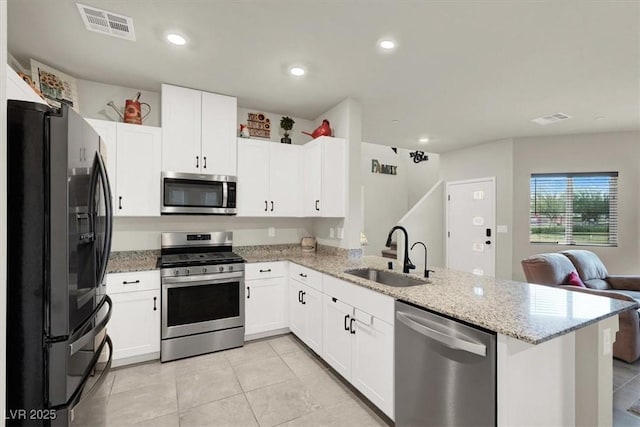 kitchen featuring visible vents, appliances with stainless steel finishes, open floor plan, a peninsula, and a sink