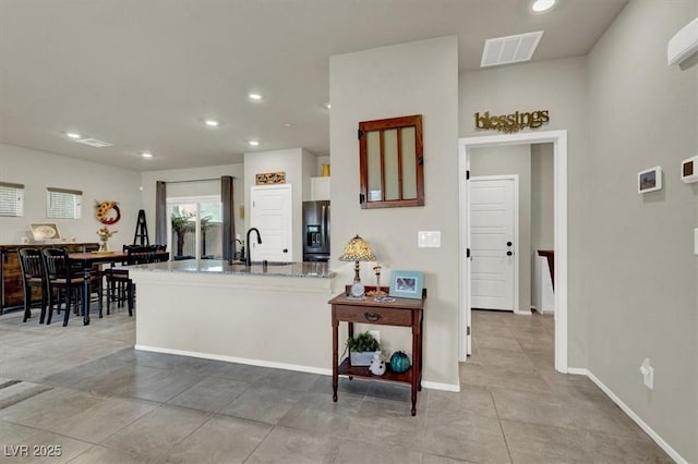 kitchen featuring recessed lighting, visible vents, refrigerator with ice dispenser, and a peninsula