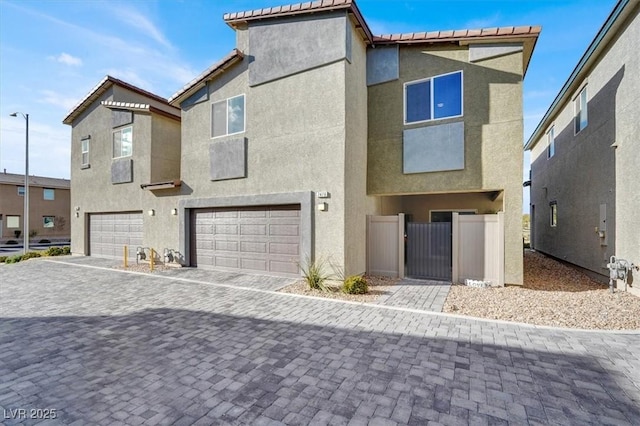 multi unit property with a garage, decorative driveway, a gate, and stucco siding